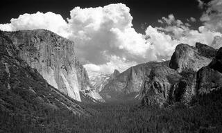 A scenic view of Yosemite Valley from Tunnel View or Inspiration Point, featuring Half Dome, Bridal Veil Falls, El Capitan, and a huge cumulus cloud.