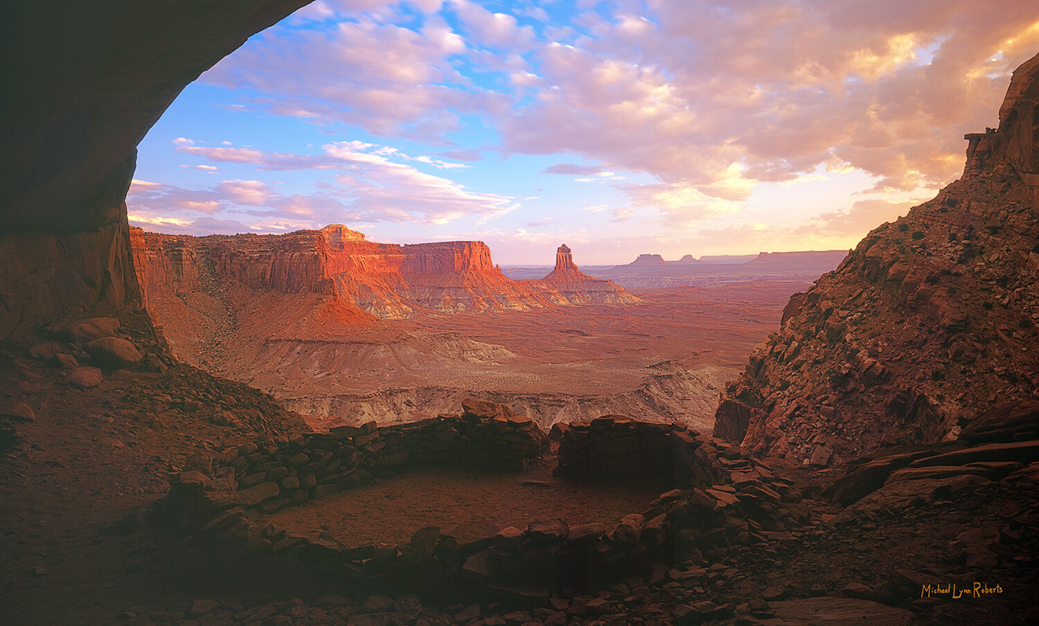 This is a sunset view from the depths of False Kiva, looking out over Soda Basin in Canyonlands National Park. The shadowed foreground...