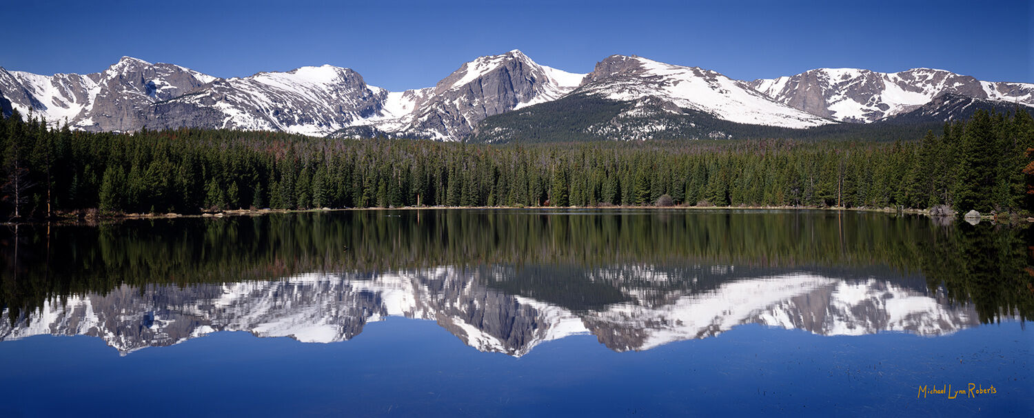 The snow-covered Rocky Mountain National Park peaks reflected in the waters of Lake Bierstadt.