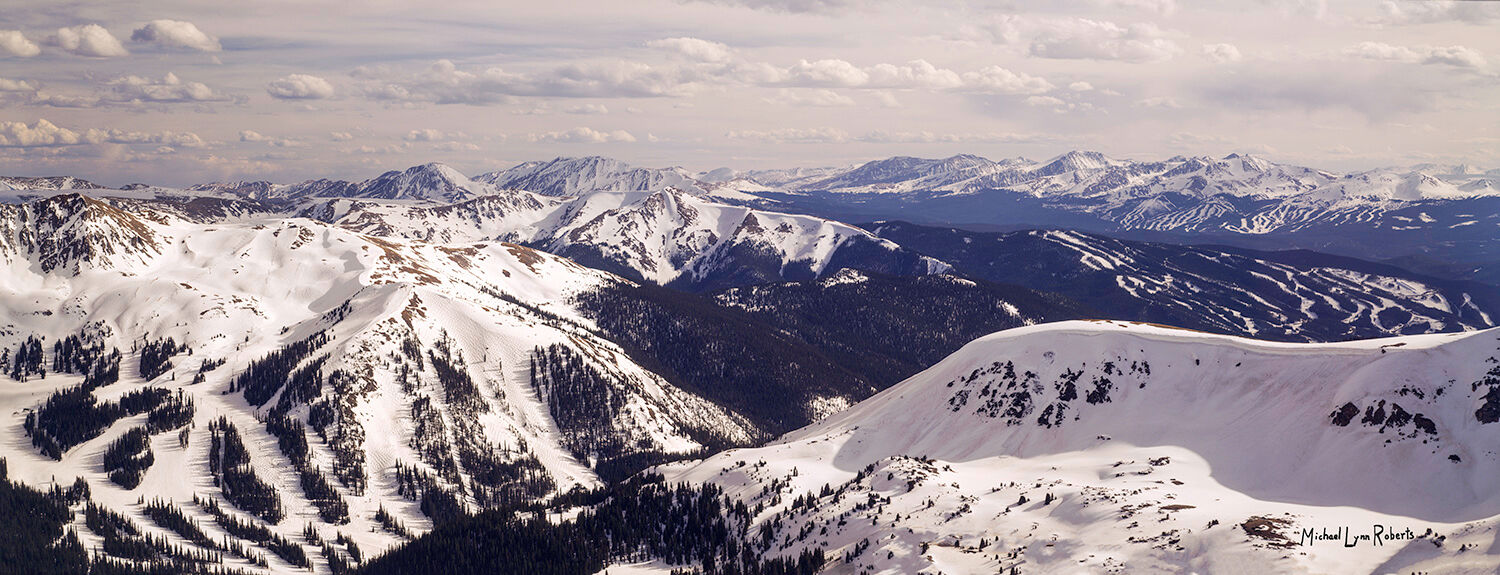 A view of snow-covered mountain peaks as far as the eye can see including Loveland Pass, Arapahoe Basin, Keystone, and Breckenridge ski mountains.