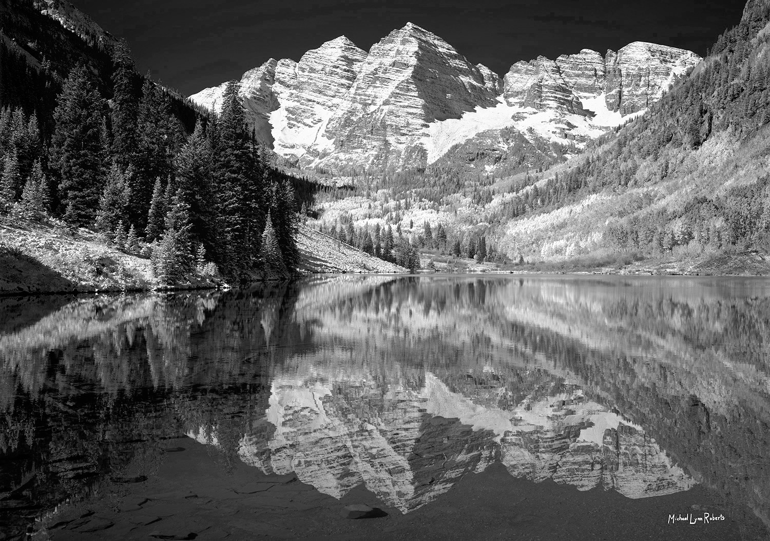 A black and white picture of the Maroon Bells twin mountain peaks with reflection in Maroon Lake, near Aspen, Colorado.